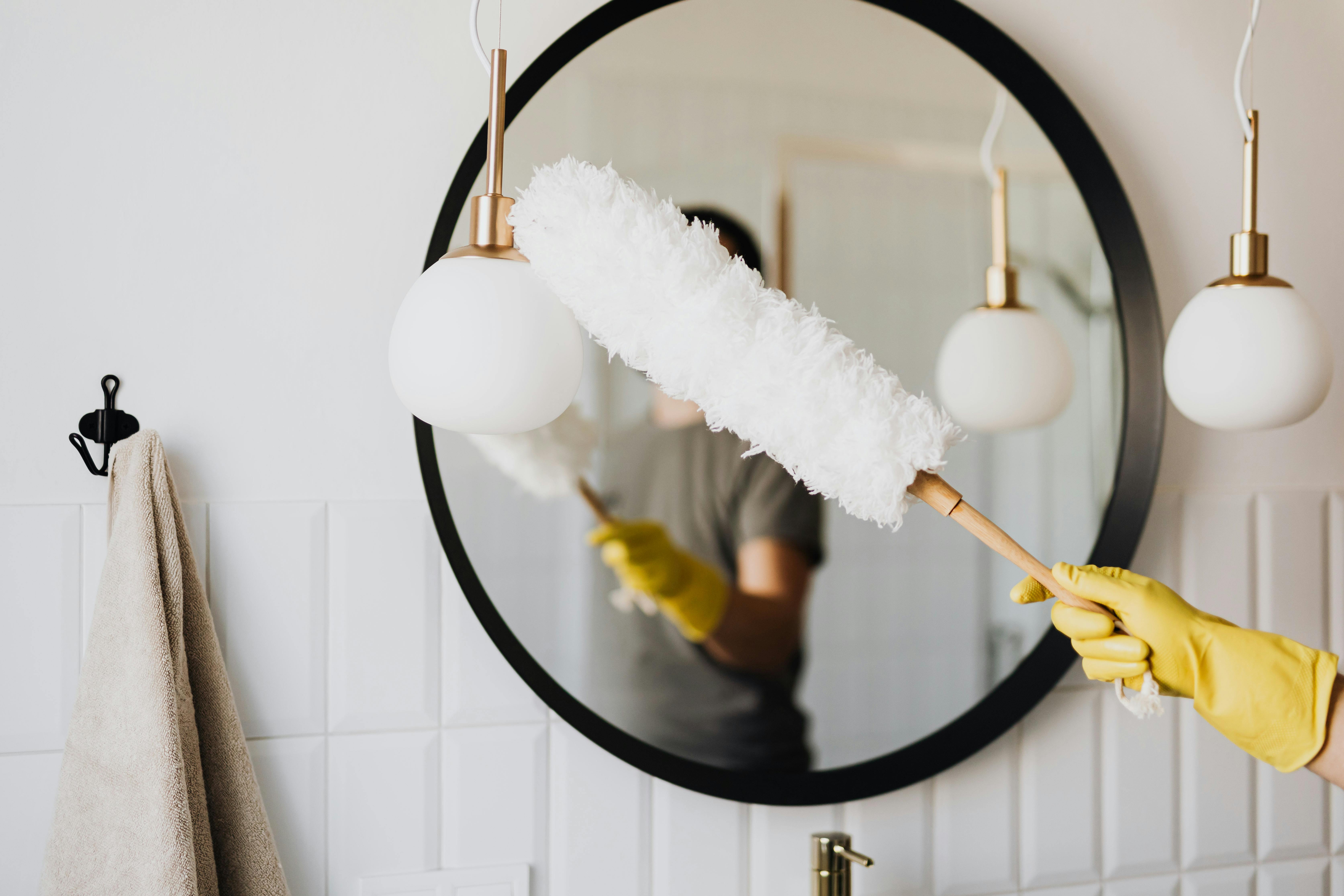 Professional cleaning service - person in yellow gloves cleaning mirror